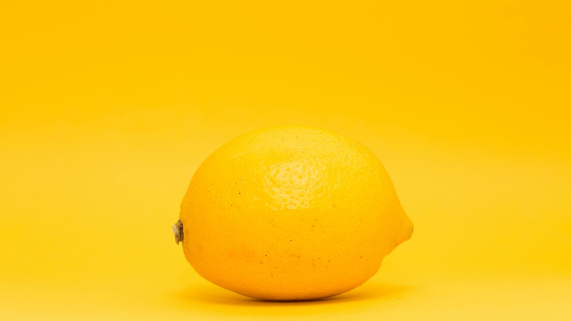 Bright lemon showcased on a uniform yellow backdrop, highlighting freshness and citrus appeal.